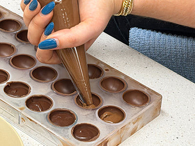 Filling chocolate mold with piping bag.