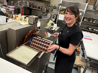 Woman smiling while making chocolates in kitchen.