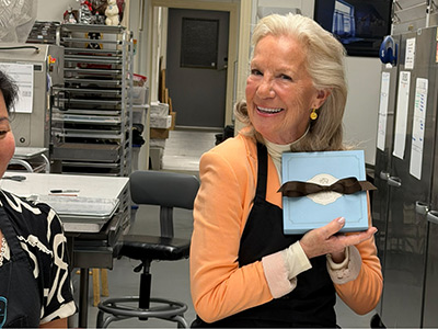 Smiling woman holding a blue gift box.