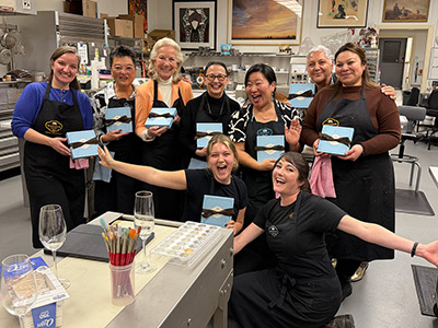 Group celebrating in art studio with paintings.
