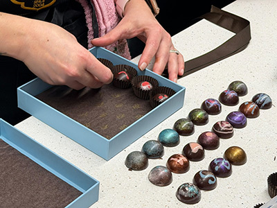 Hand arranging chocolates in a blue box.