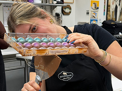 Woman holding tray of colorful chocolates.