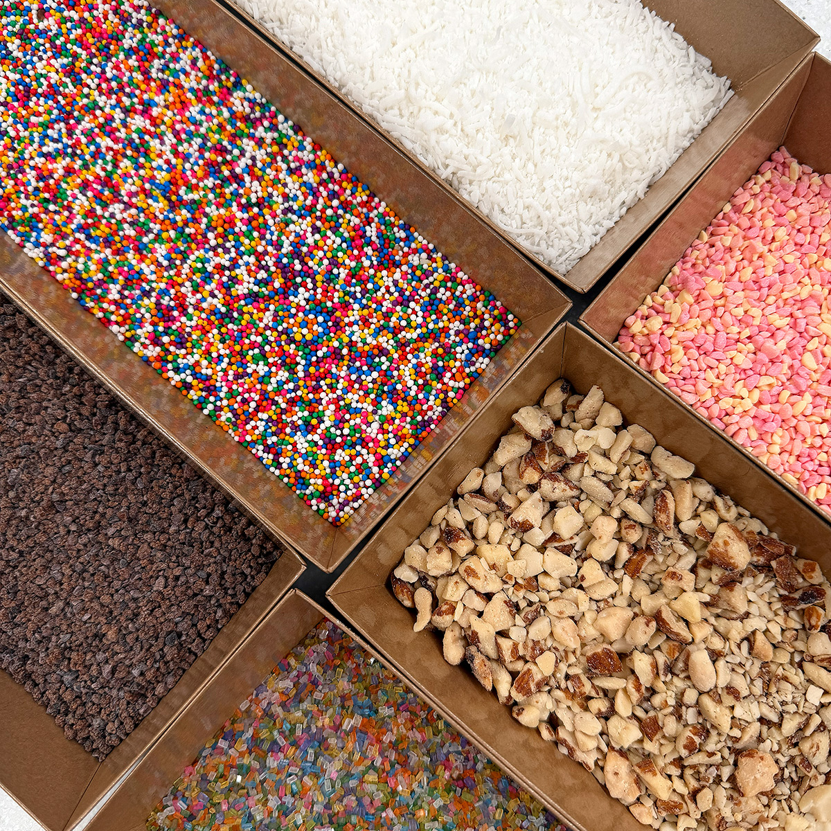 Boxes filled with various colorful and textured toppings.